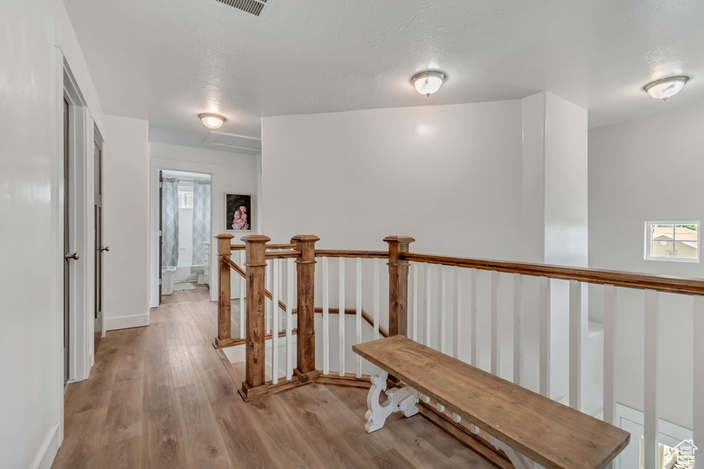 Hallway with light wood-style floors, an upstairs landing, healthy amount of natural light, and a textured ceiling