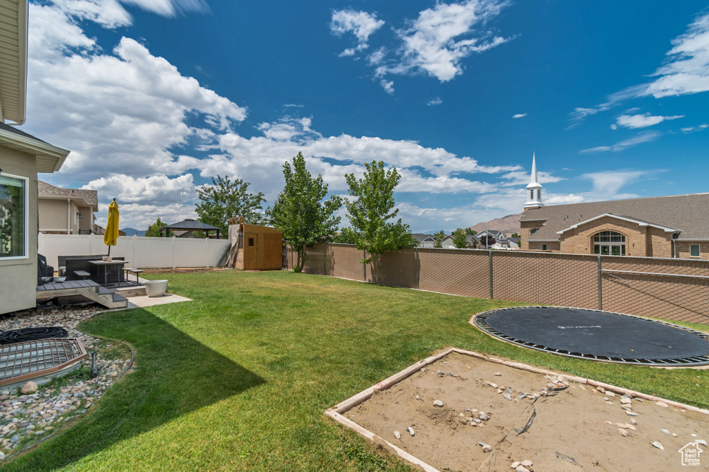 Fenced backyard featuring a shed and a trampoline
