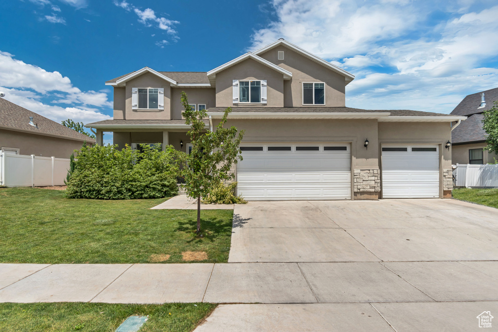 Traditional-style house with stucco siding, concrete driveway, an attached garage, and stone siding