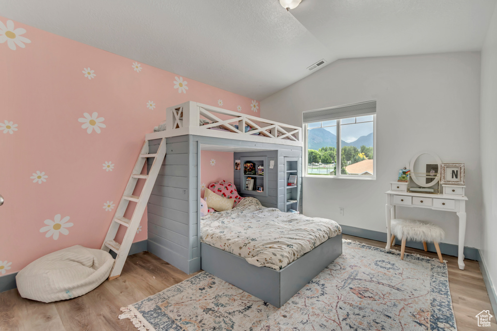 Bedroom featuring wood finished floors and lofted ceiling
