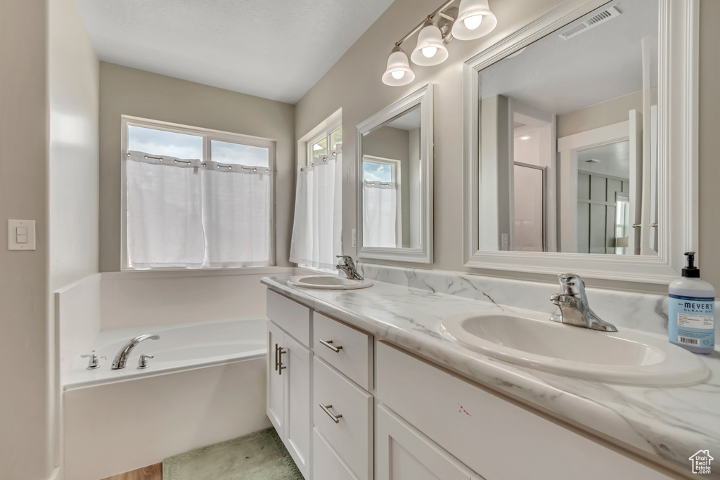 Full bath featuring double vanity and a garden tub