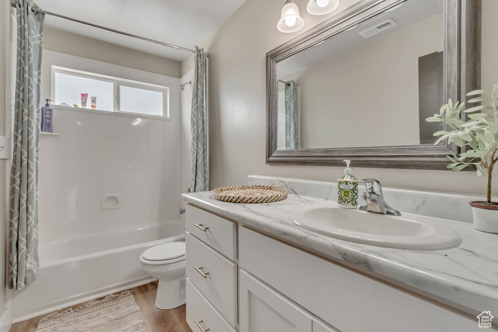 Bathroom with vanity, wood finished floors, and shower / bath combo with shower curtain
