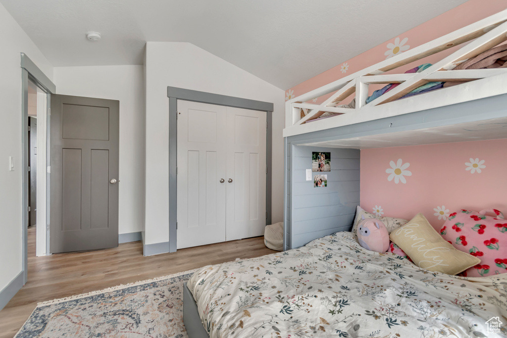 Bedroom featuring light wood-type flooring, lofted ceiling, and a closet