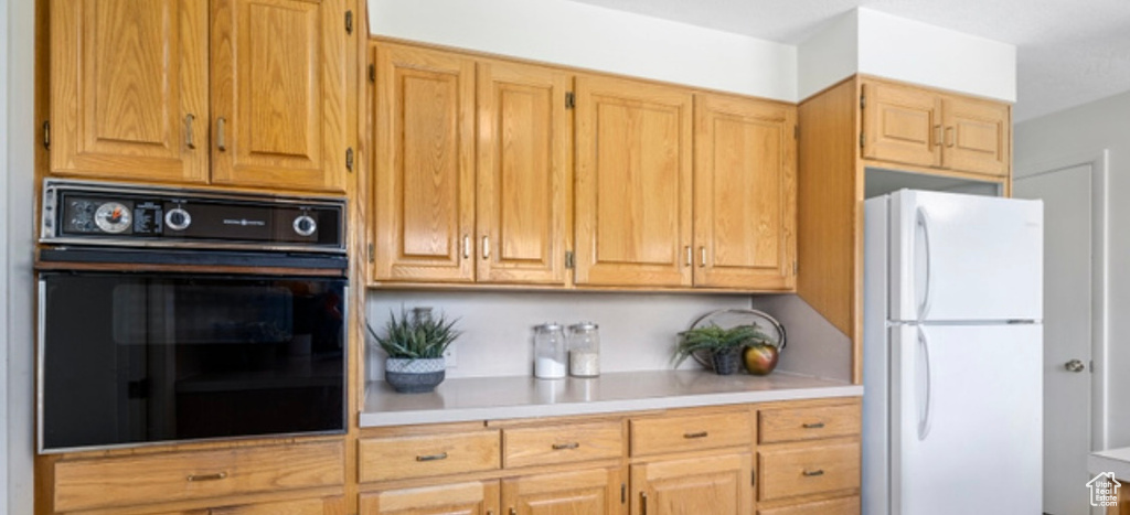 Kitchen with oven, freestanding refrigerator, and light countertops