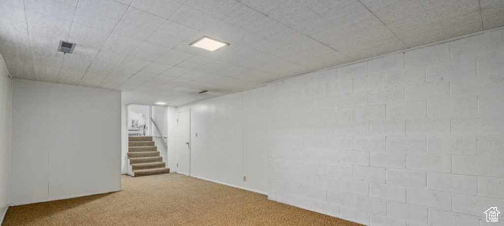Finished basement featuring carpet flooring, stairway, and concrete block wall