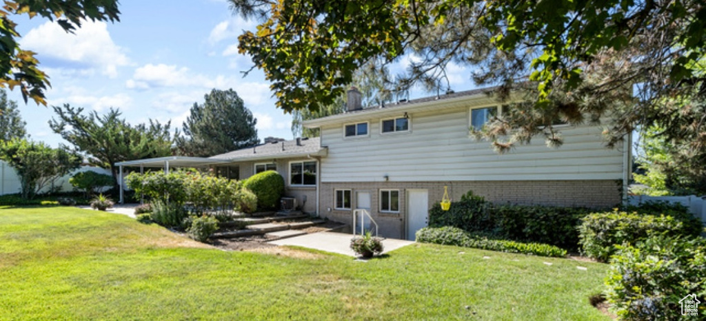Back of property with a lawn, brick siding, and a patio