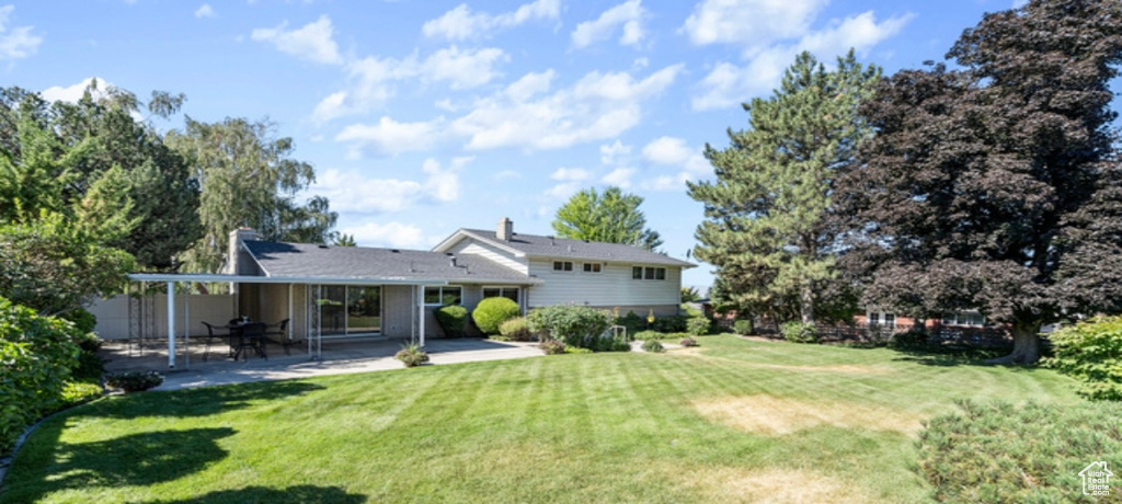 Rear view of house with a patio area and a yard