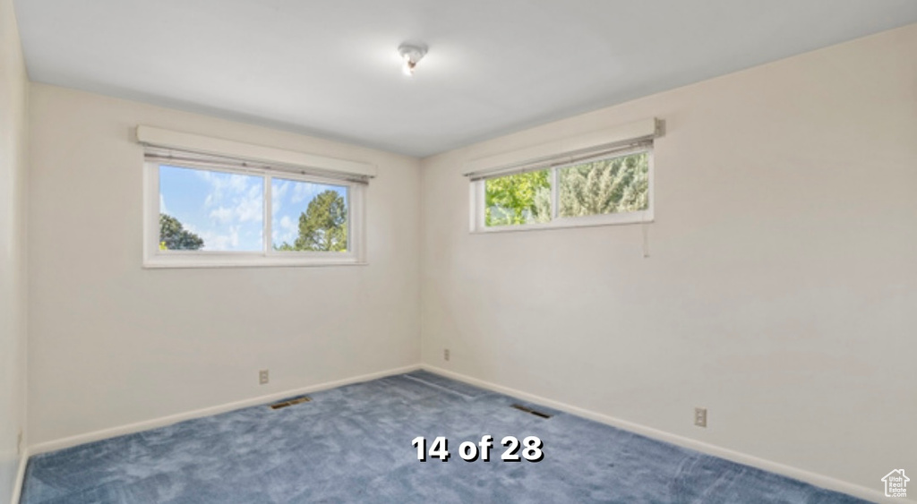Carpeted spare room featuring baseboards
