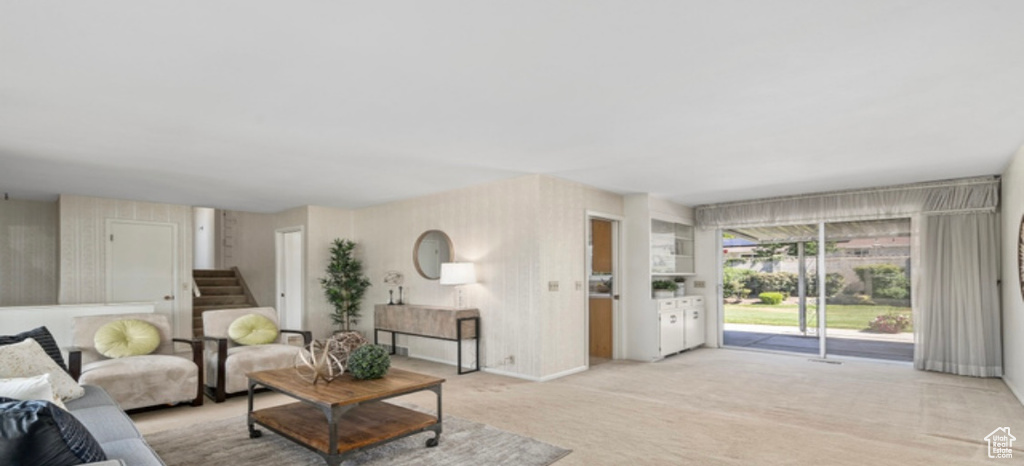 Living area with light colored carpet, stairs, and wallpapered walls