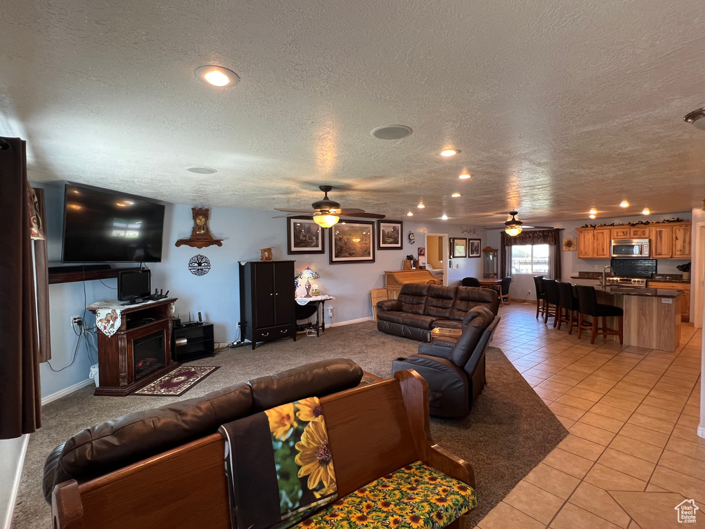 Living area with a ceiling fan, a textured ceiling, and light tile patterned floors