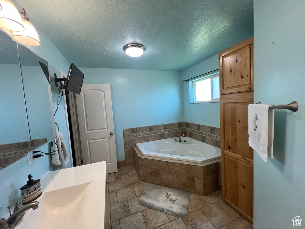 Bathroom featuring a garden tub, a textured ceiling, and vanity