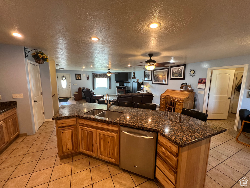 Kitchen with dishwasher, a textured ceiling, open floor plan, brown cabinets, and a ceiling fan