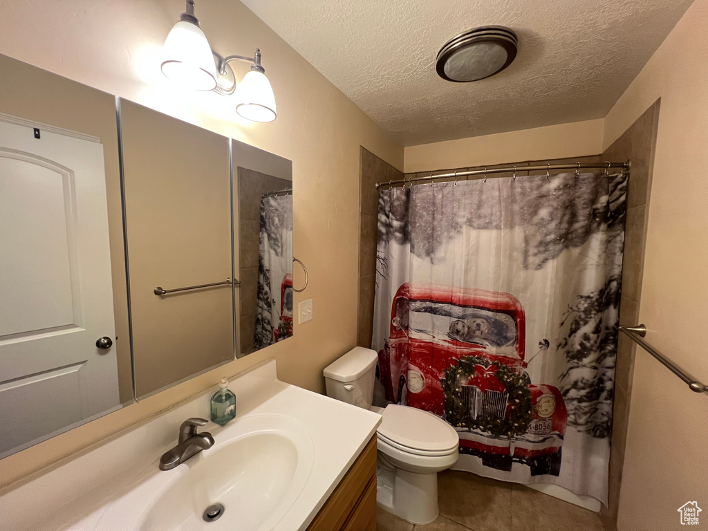 Full bath with vanity, a textured ceiling, tile patterned floors, and curtained shower