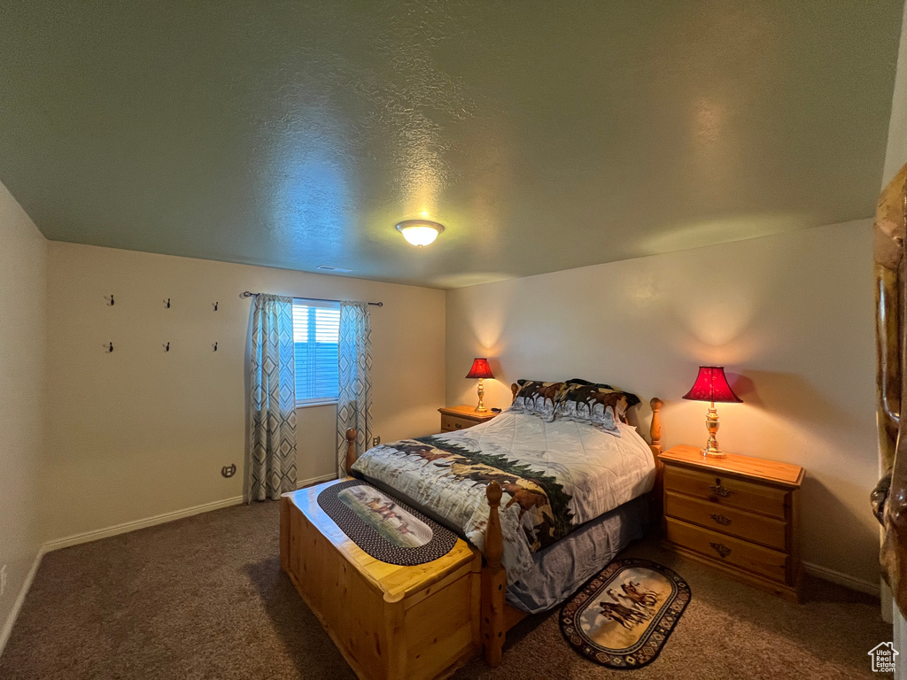 Carpeted bedroom featuring baseboards and a textured ceiling