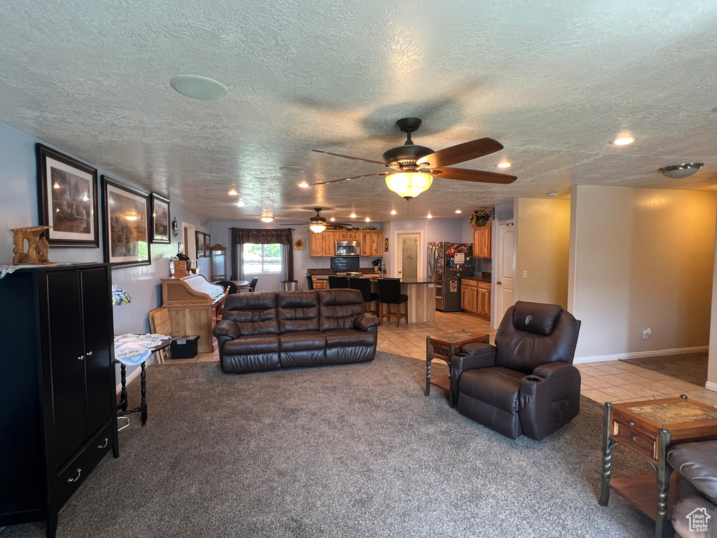 Living area featuring light carpet, a textured ceiling, ceiling fan, light tile patterned floors, and recessed lighting