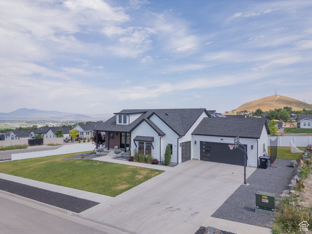 Modern farmhouse style home featuring a mountain view, a residential view, an attached garage, driveway, and roof with shingles