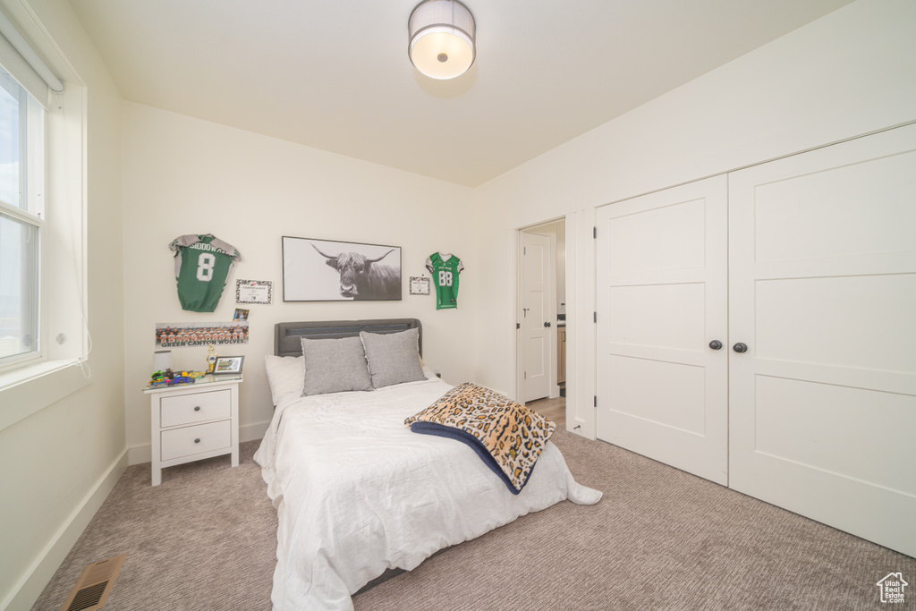 Bedroom with light carpet and a closet