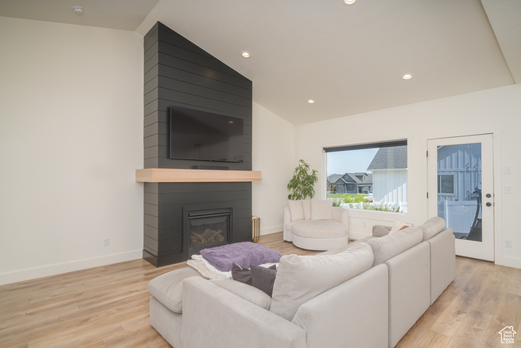 Living room featuring light wood-style floors, a fireplace, recessed lighting, and vaulted ceiling