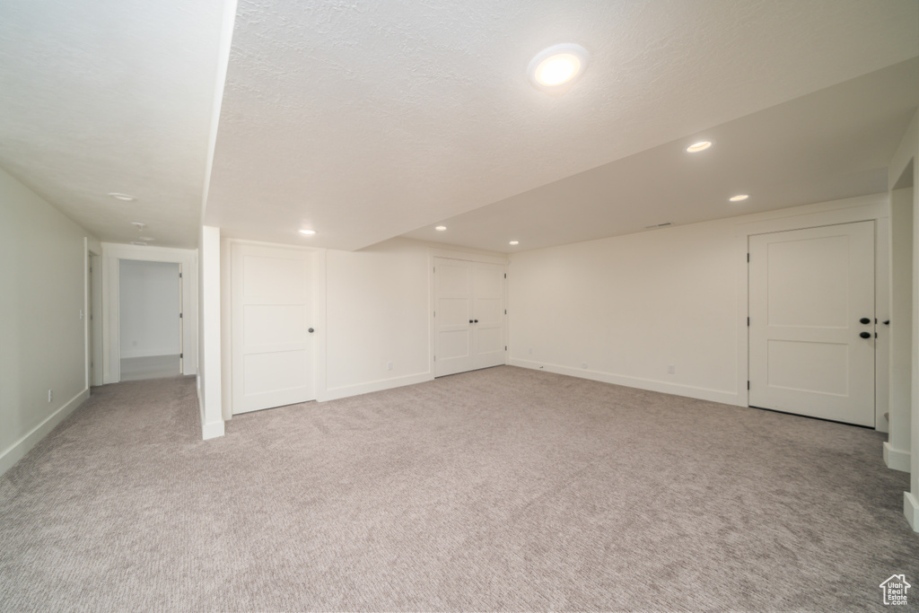 Finished below grade area with light colored carpet and recessed lighting