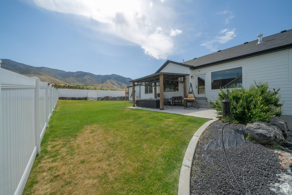 Fenced backyard featuring a mountain view, a patio area, and entry steps