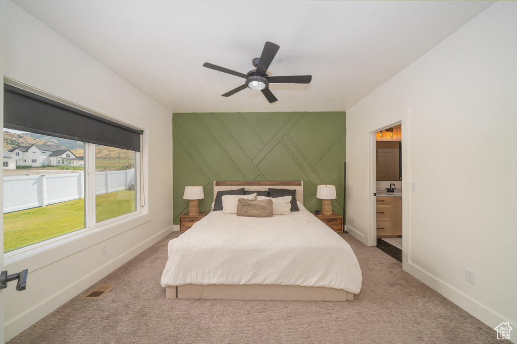 Bedroom featuring light colored carpet, connected bathroom, and a ceiling fan