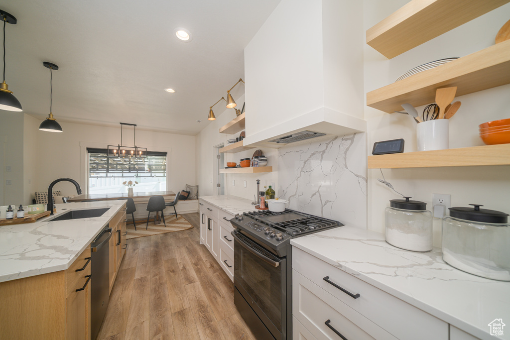 Kitchen featuring open shelves, black gas range oven, stainless steel dishwasher, light wood-style floors, and light stone counters