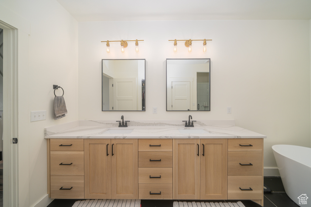 Full bathroom with double vanity, a soaking tub, and tile patterned flooring