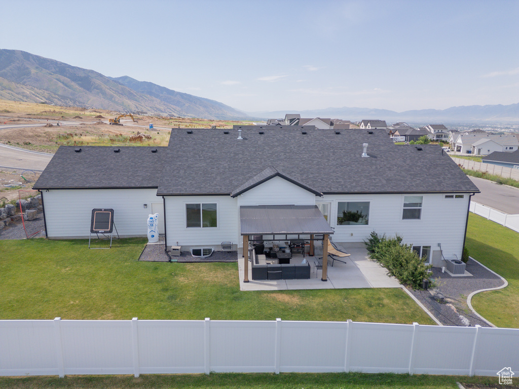 Back of property featuring a fenced backyard, a patio, a mountain view, and a shingled roof