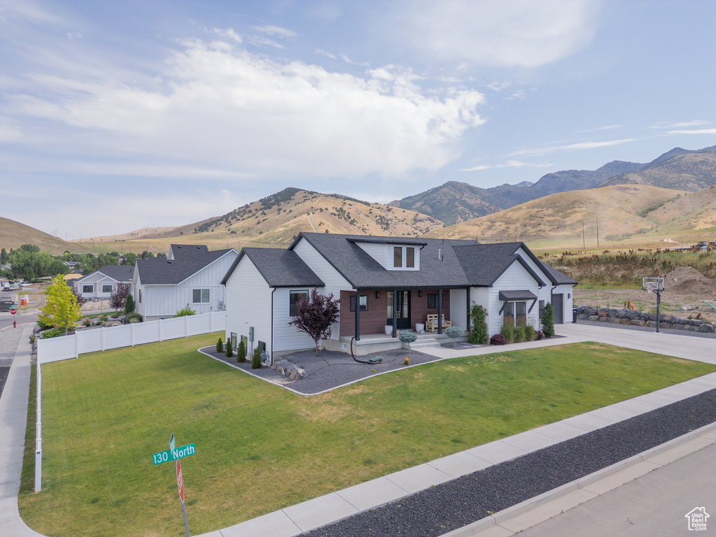 Modern farmhouse featuring a mountain view, driveway, covered porch, and a garage