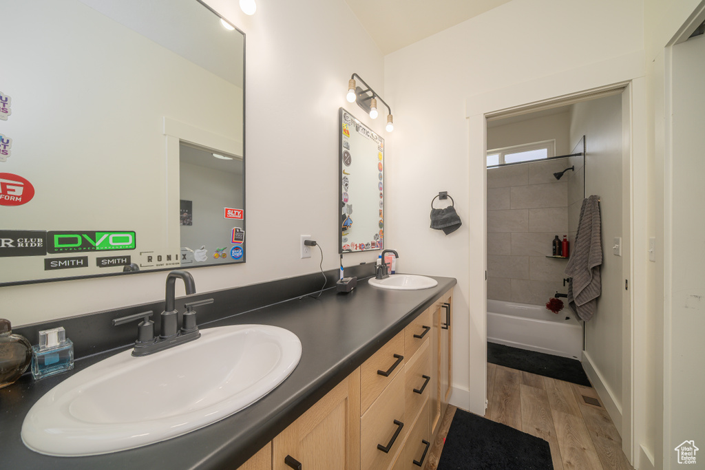 Full bath with double vanity, wood finished floors, and tub / shower combination