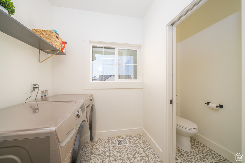 Laundry area with separate washer and dryer and light tile patterned floors