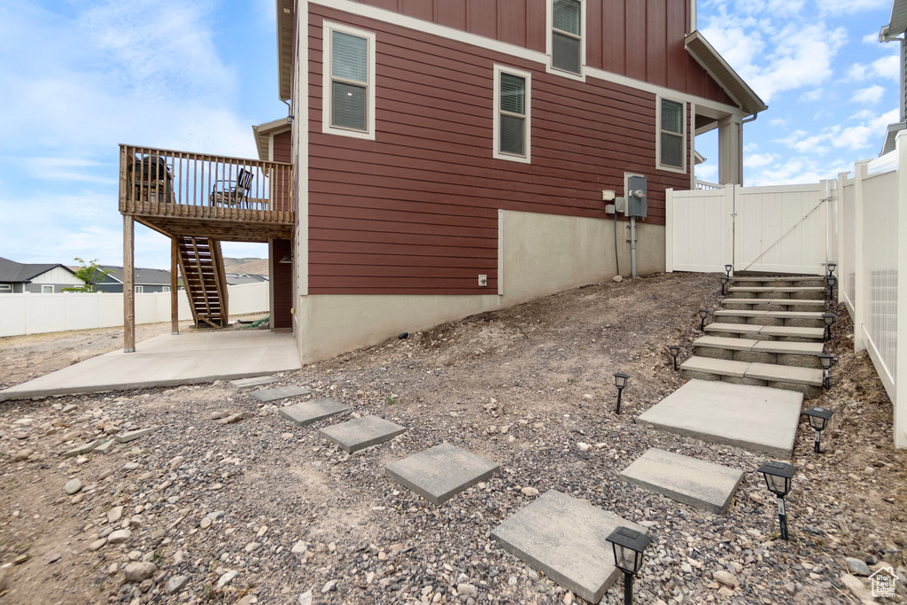 View of home\\\'s exterior featuring stairs, board and batten siding, a patio, a deck, and a gate