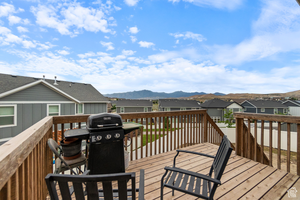 Wooden deck featuring a residential view, a mountain view, and grilling area