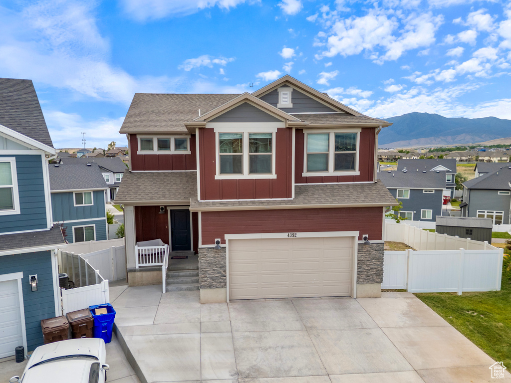 View of front of property with board and batten siding, a mountain view, a residential view, an attached garage, and stone siding