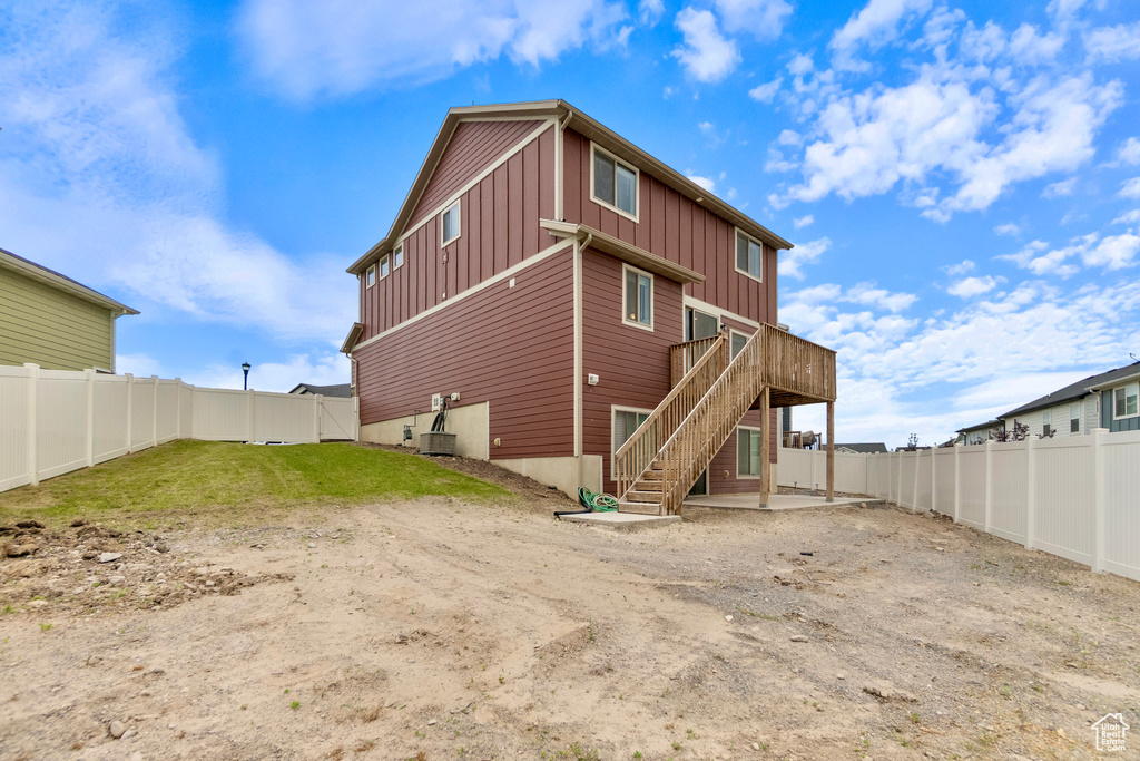 Back of house with board and batten siding, stairs, a fenced backyard, and a deck