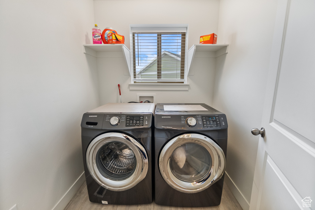 Laundry area with washing machine and clothes dryer and wood finished floors
