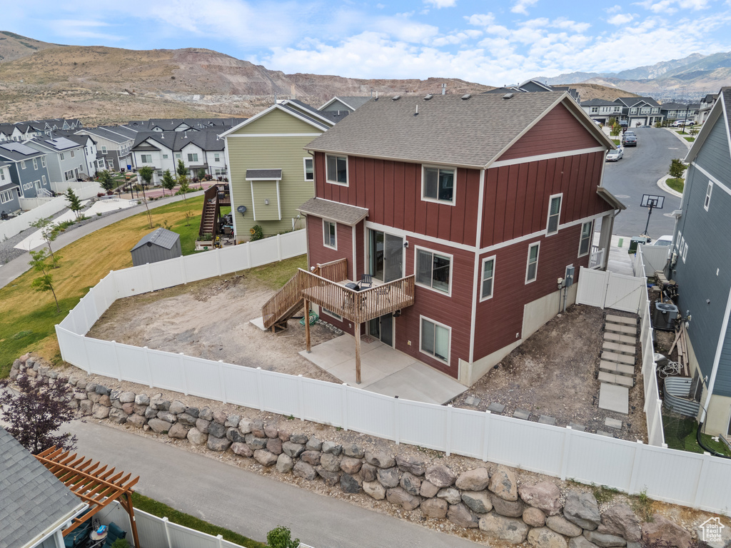 Rear view of property featuring a residential view, a deck with mountain view, stairs, a shingled roof, and a fenced backyard