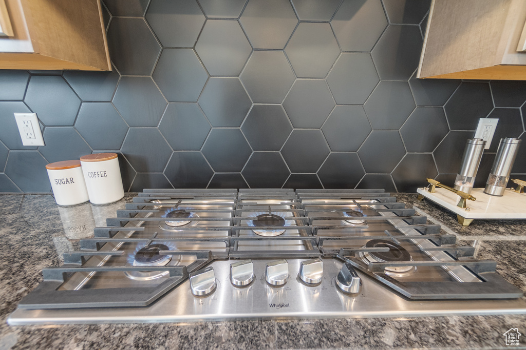 Kitchen view of stainless steel gas stovetop and decorative backsplash
