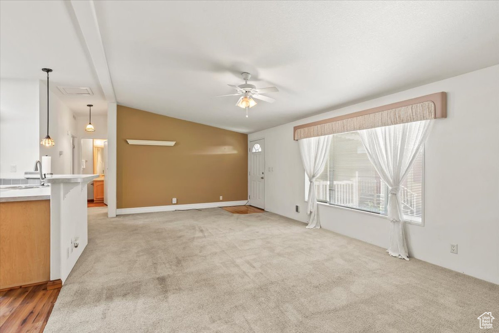 Unfurnished living room with ceiling fan, lofted ceiling, and light colored carpet