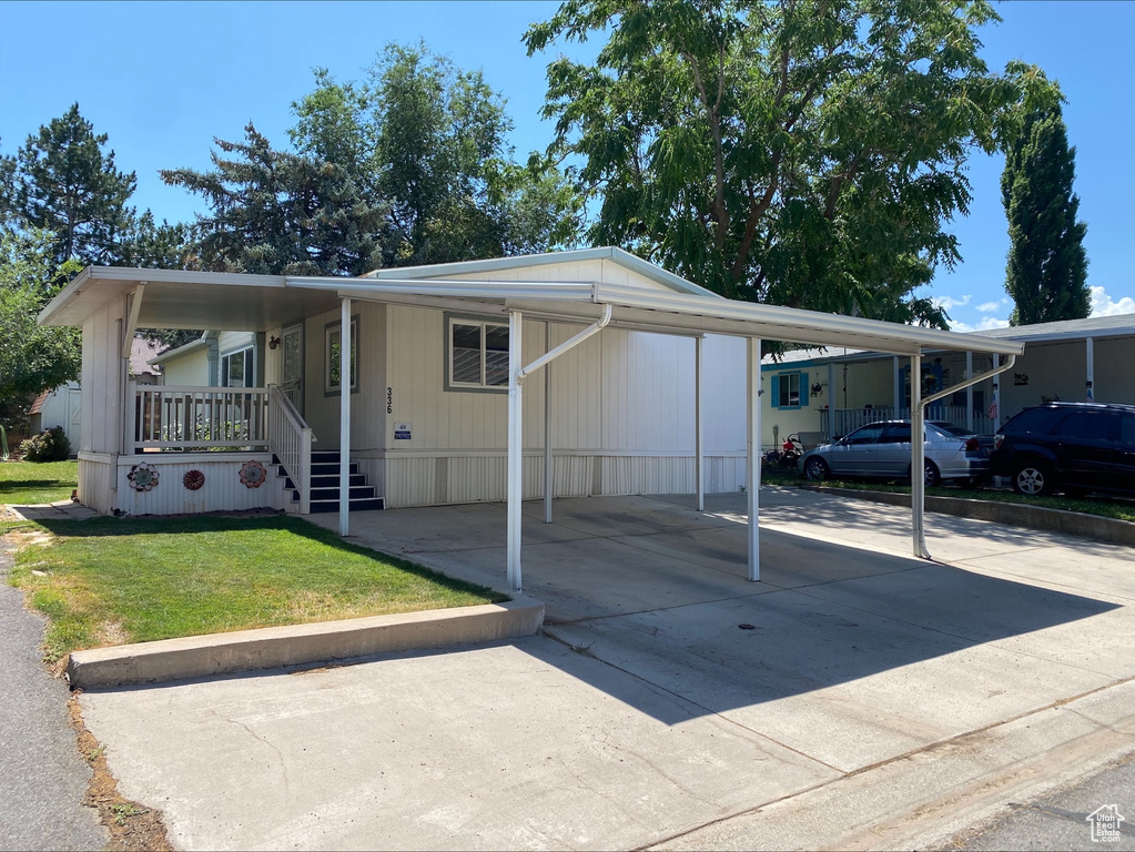 Manufactured / mobile home featuring driveway, a front lawn, and an attached carport