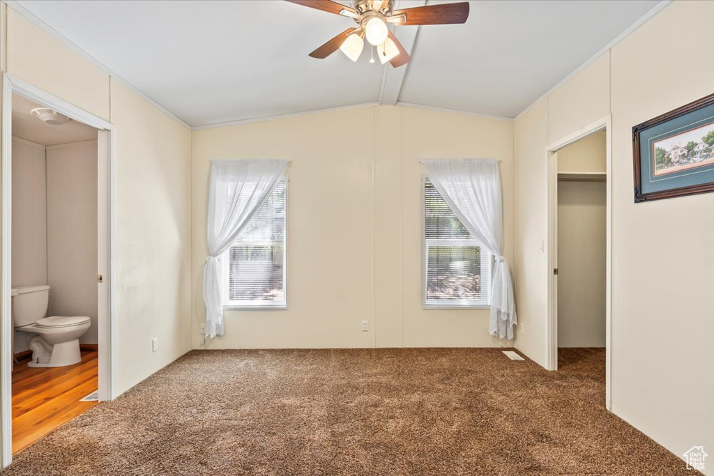 Unfurnished bedroom with carpet, lofted ceiling, a spacious closet, ensuite bath, and ceiling fan