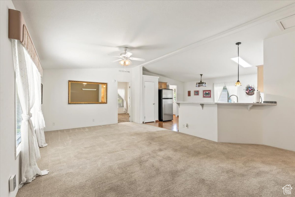 Unfurnished living room with carpet floors, vaulted ceiling, and ceiling fan
