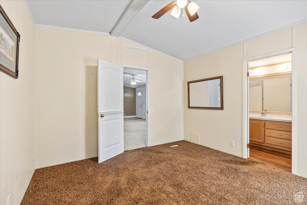 Unfurnished bedroom featuring vaulted ceiling, carpet, ensuite bathroom, and a ceiling fan