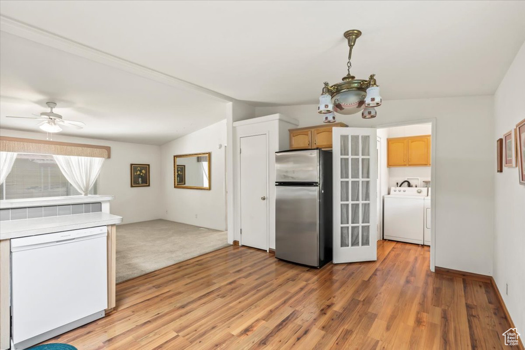 Kitchen with freestanding refrigerator, white dishwasher, separate washer and dryer, and light wood-type flooring