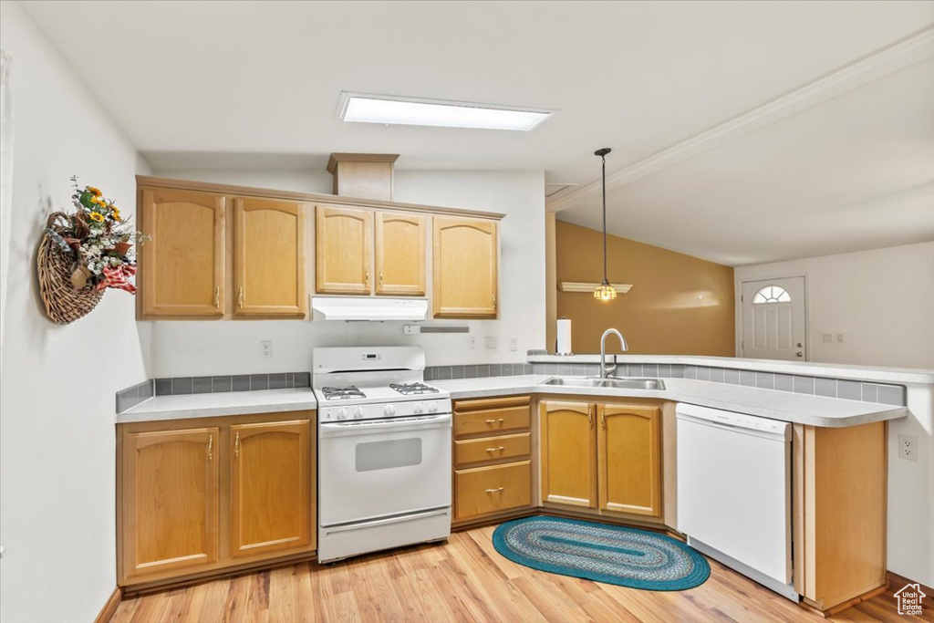 Kitchen featuring white appliances, a peninsula, under cabinet range hood, light wood-style floors, and vaulted ceiling