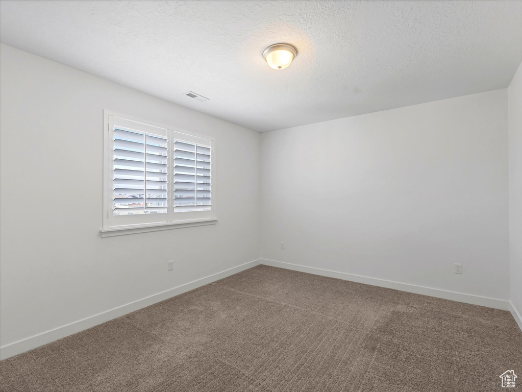 Carpeted spare room featuring baseboards