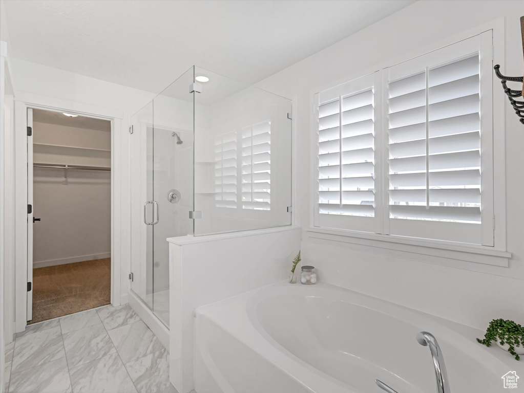 Bathroom featuring a garden tub, a shower stall, a spacious closet, and marble finish floors
