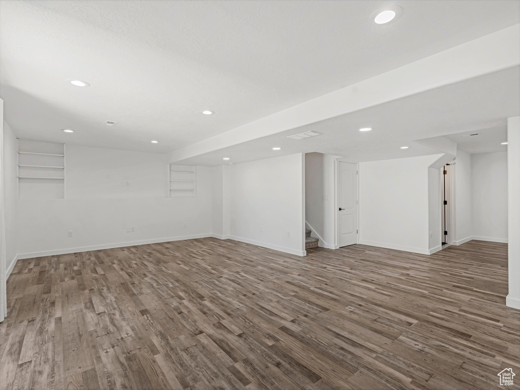 Finished below grade area with wood finished floors, stairway, and recessed lighting