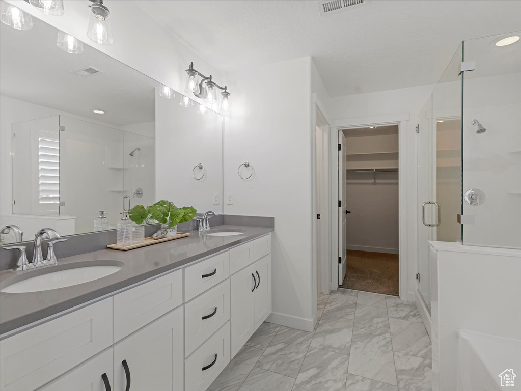 Full bath with a shower stall, marble look tile flooring, double vanity, a spacious closet, and recessed lighting