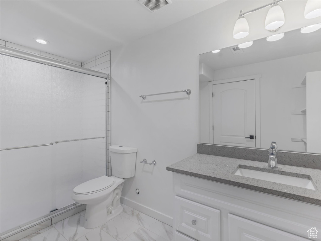 Bathroom featuring vanity, a stall shower, marble look tile flooring, and recessed lighting